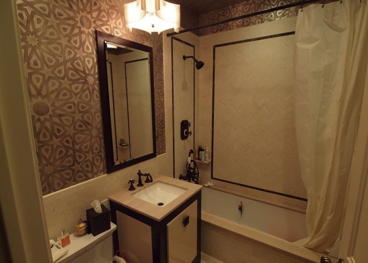 A vintage-style bathroom with patterned wallpaper and a bathtub.