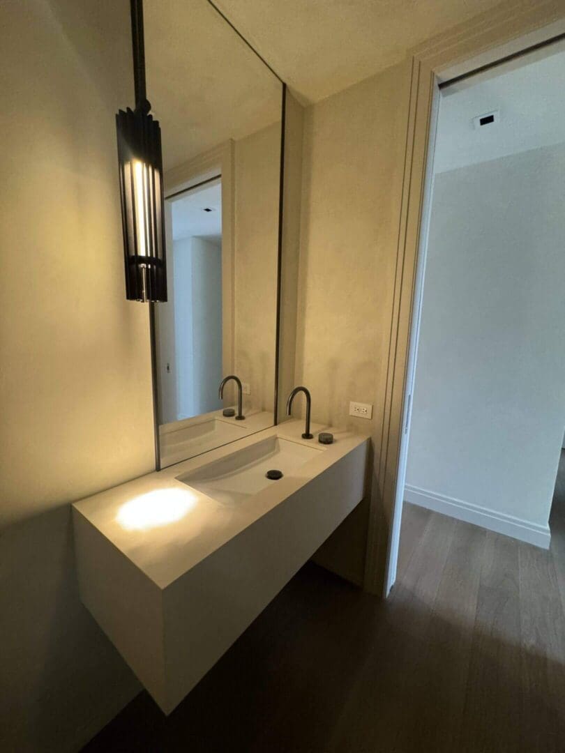 Modern bathroom sink area with dual faucets and warm lighting.