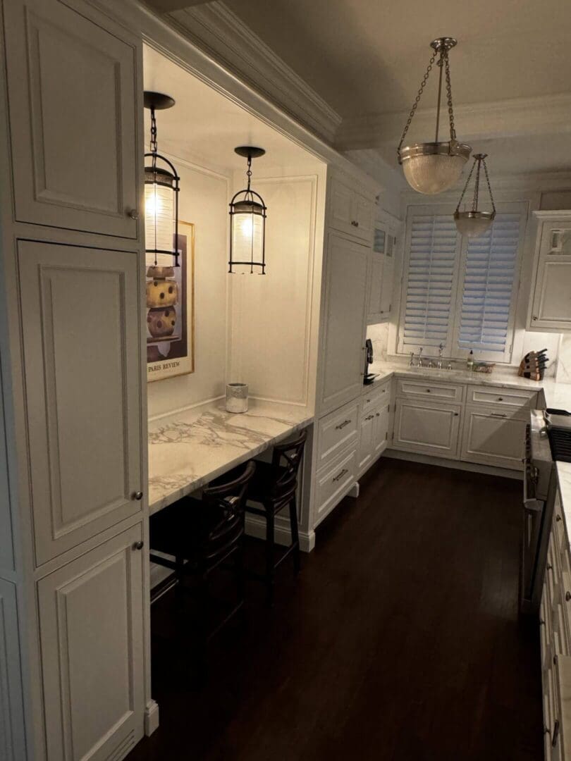 Elegant kitchen with white cabinetry, dark wood floors, and a cozy desk nook.