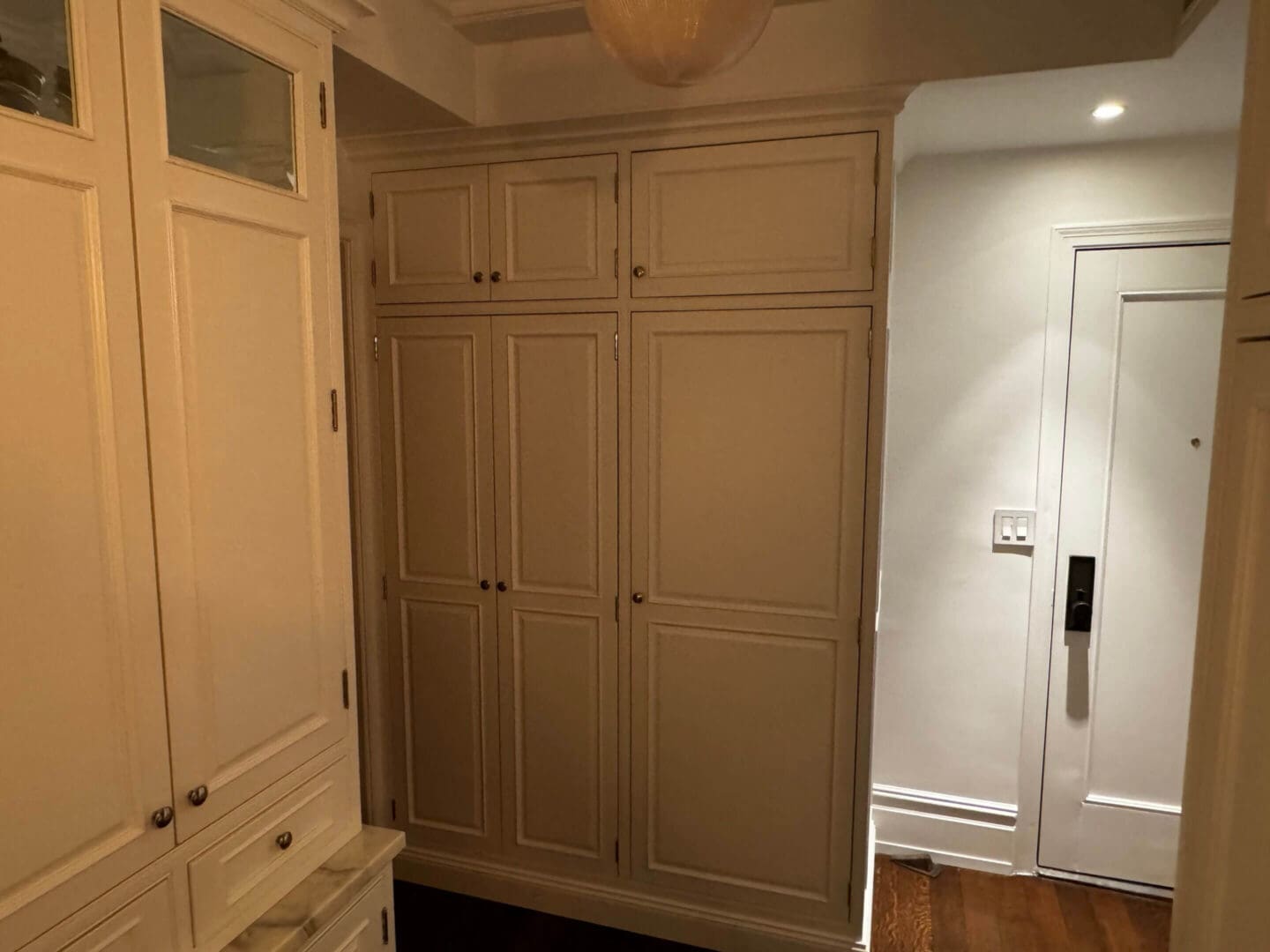 A corner with beige built-in cabinets and a white door in a cozy room.