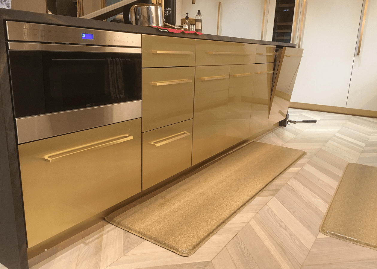 Modern kitchen cabinets with a built-in microwave and a wooden mat on the floor.