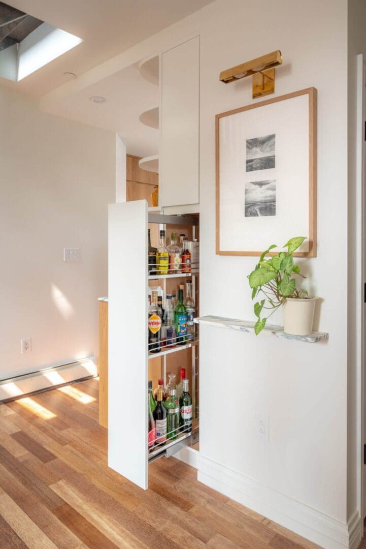 A narrow pantry shelf filled with various food items and a plant on the side.