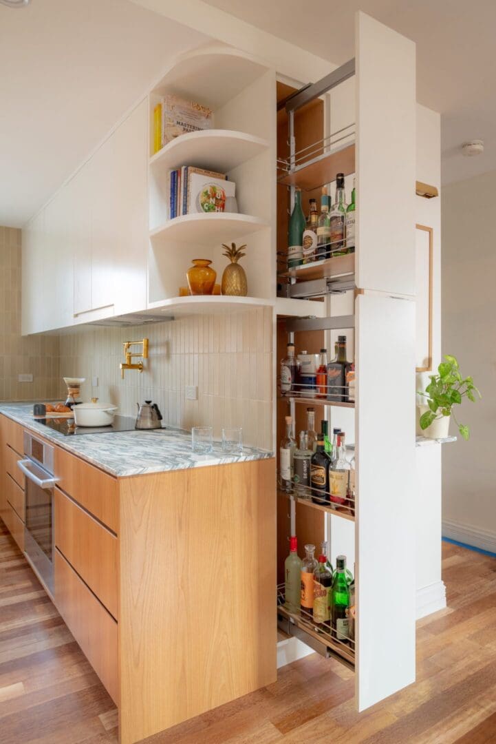 Modern kitchen corner with wooden cabinets and open pantry.