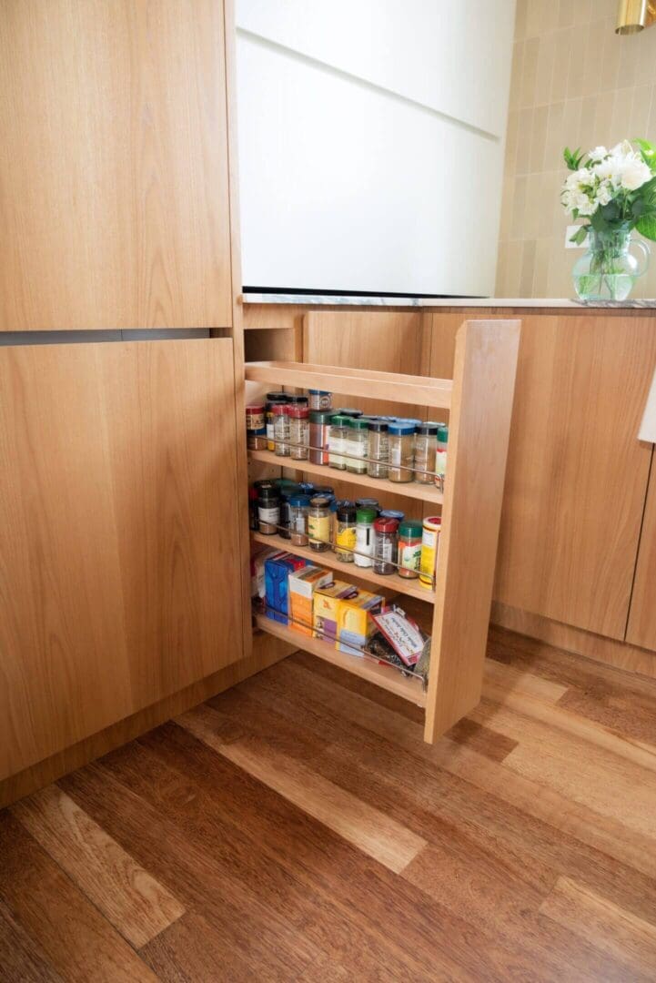 A pull-out kitchen cabinet shelf with spices and food items.