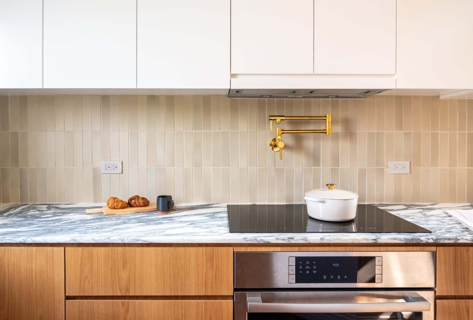 Modern kitchen countertop with stove, pot, and cutting board with bread.