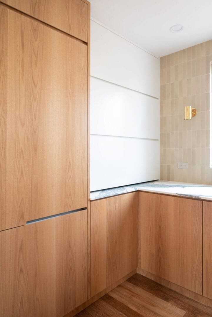 Modern kitchen corner with wood cabinetry and white countertop.