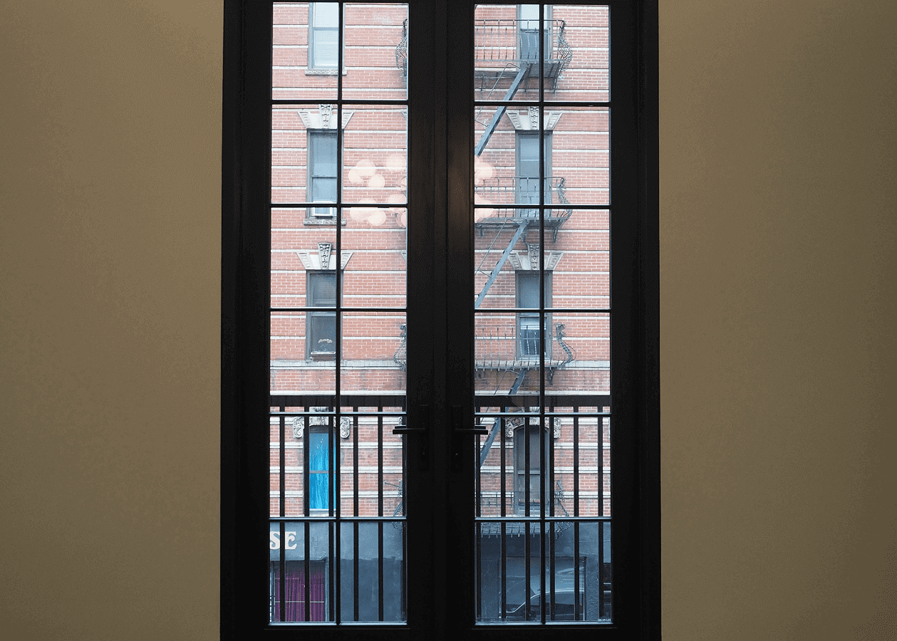 View through a glass door showing a fire escape on a brick building.
