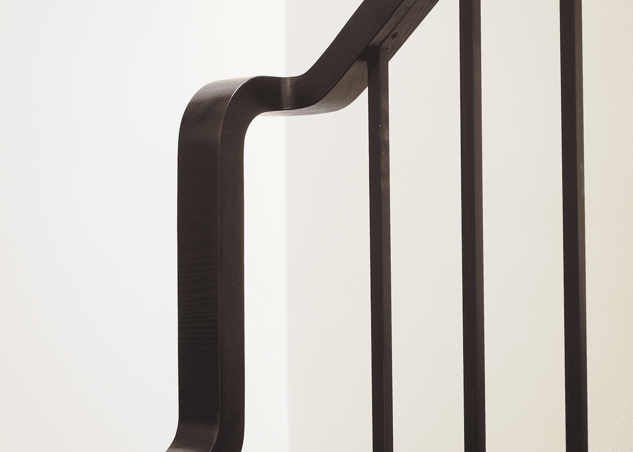Close-up of a modern black metal handrail with smooth curves and vertical bars.