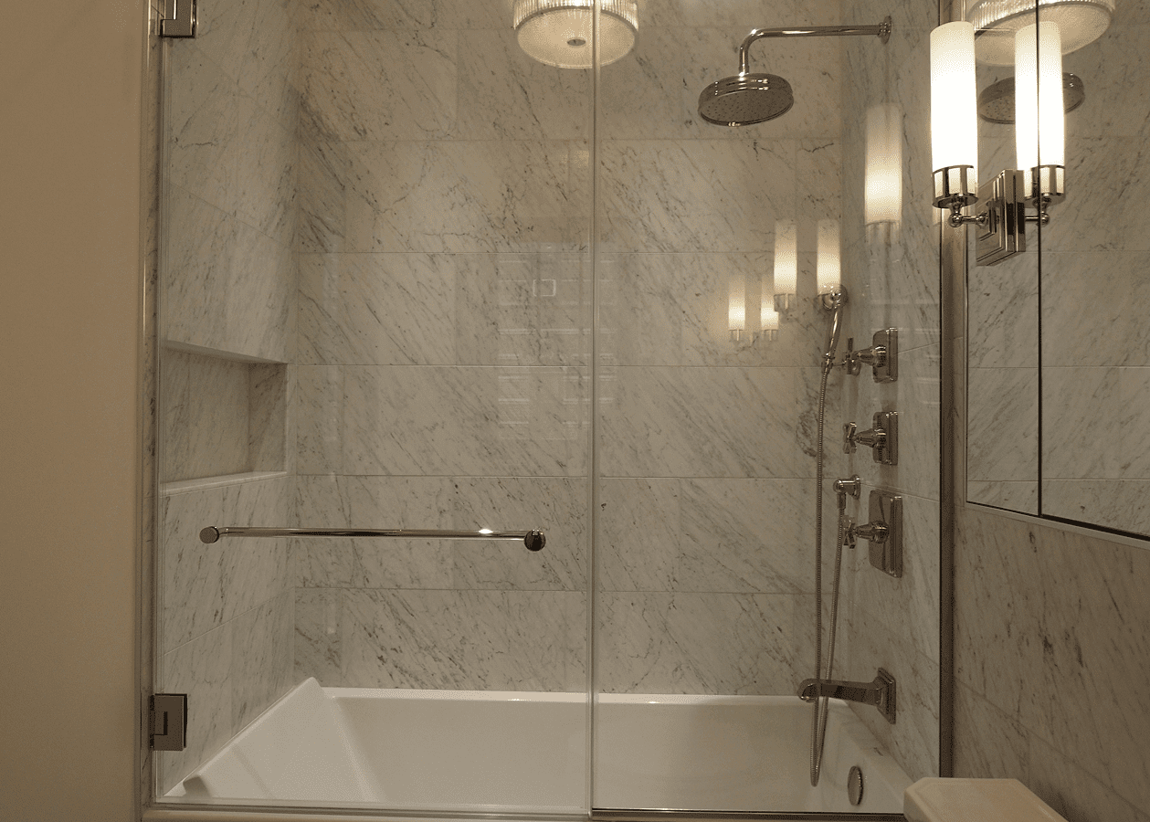 Luxurious bathroom with marble walls and a glass-enclosed shower.