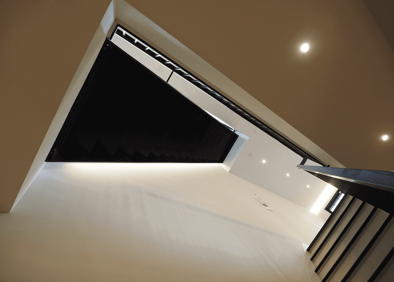 Modern stairwell with black window coverings and ceiling lights.