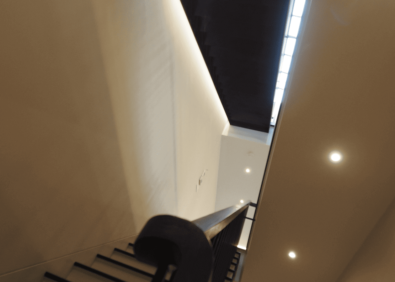 Man sitting on stairs in a modern, softly lit indoor space.