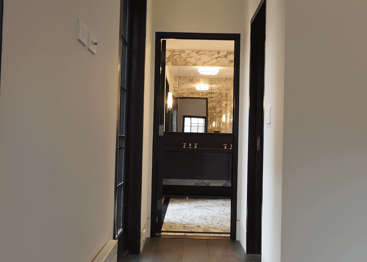 View through an open door into a warmly lit bathroom with elegant fixtures.