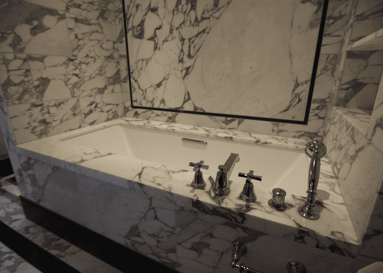Luxurious marble bathtub with elegant fixtures and a framed mirror.