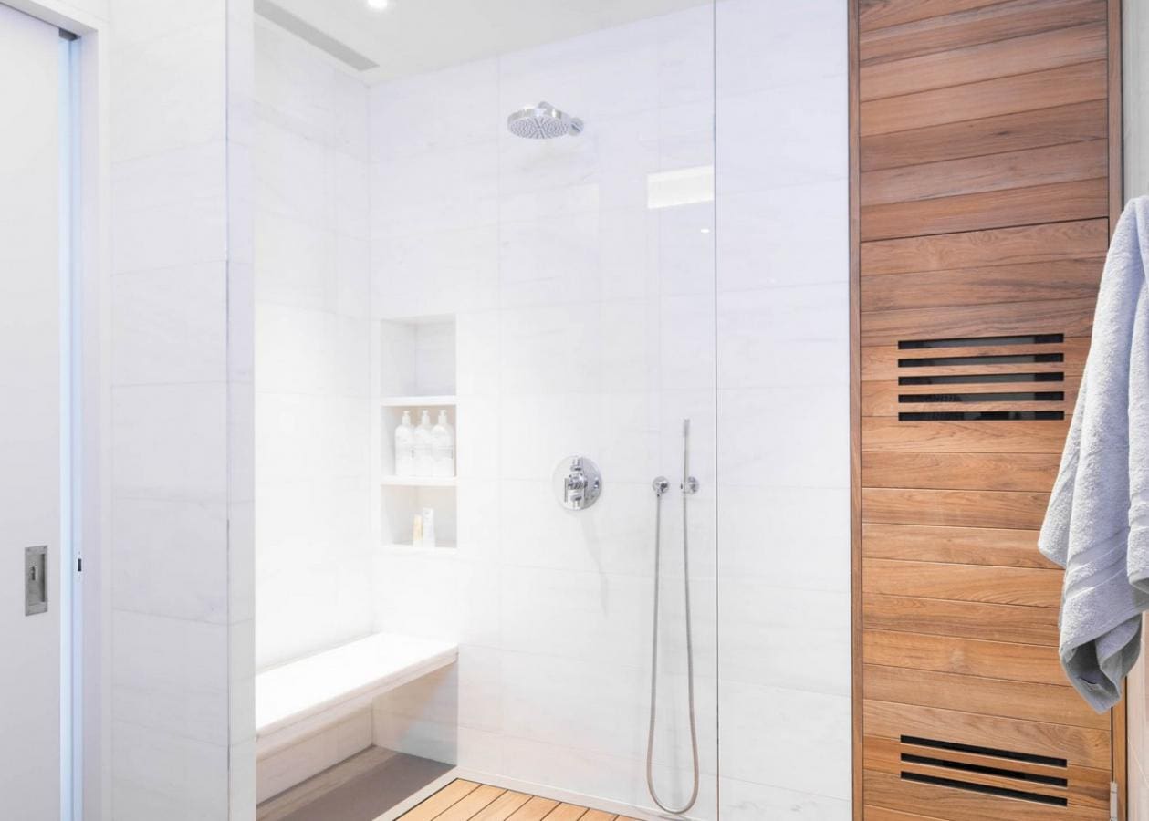 Modern bathroom shower with glass door and wooden accents.