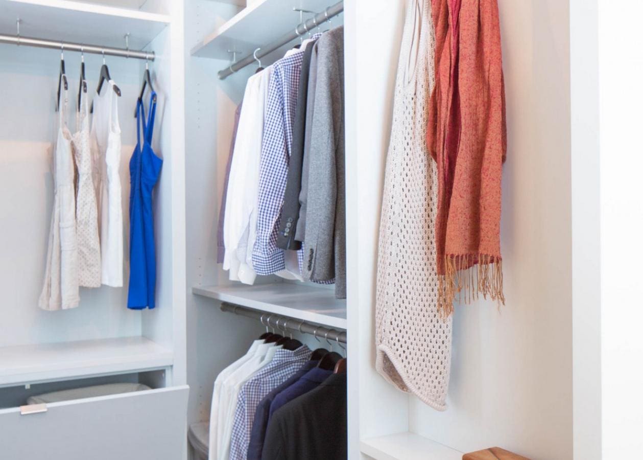 Organized closet with hanging clothes and scarves.