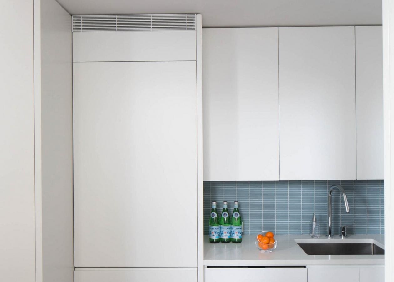 Modern kitchen with white cabinets and blue tiled backsplash.