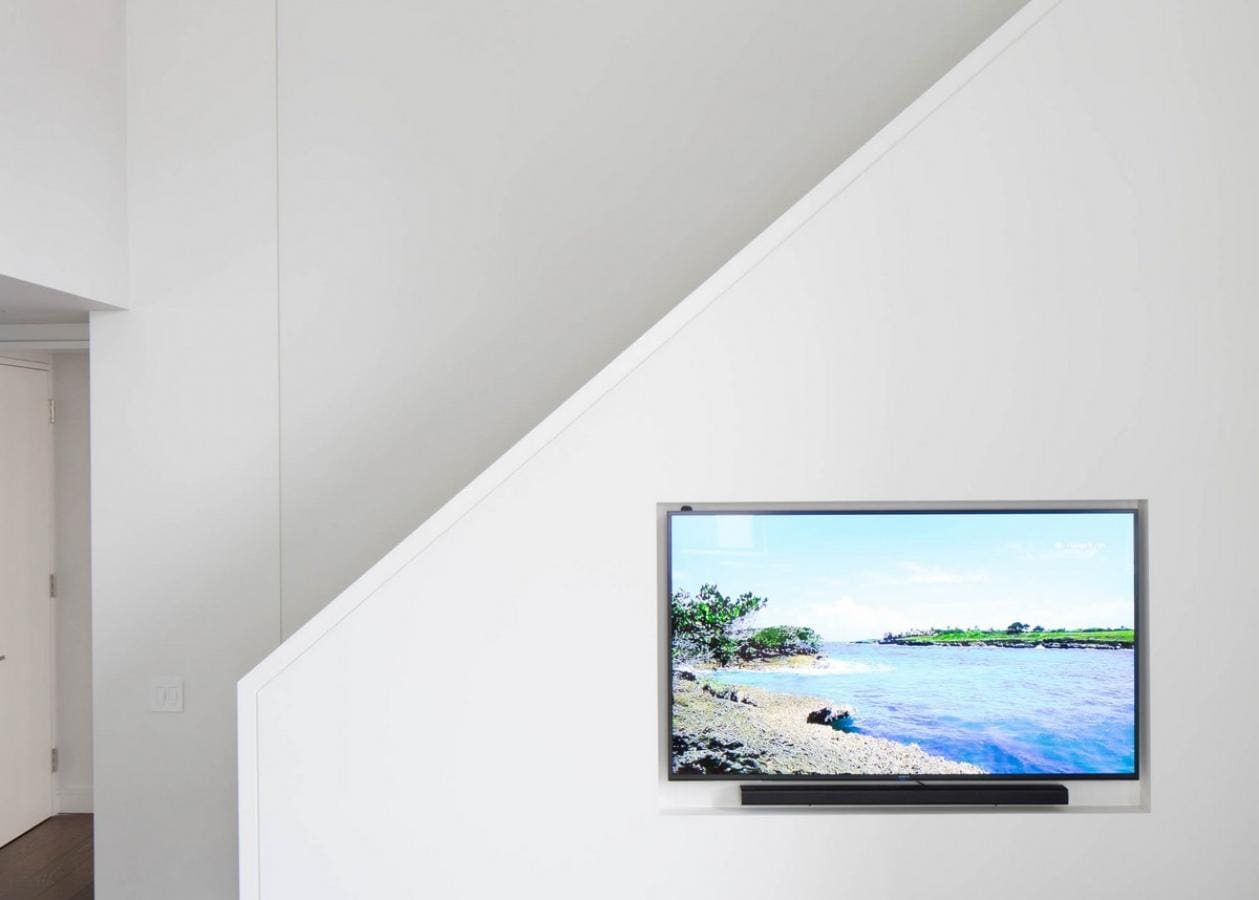 Modern TV mounted on a white slanted wall.
