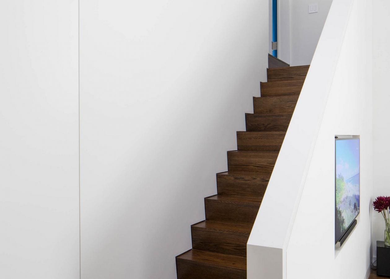 Modern wooden staircase with white walls and a blue handrail.