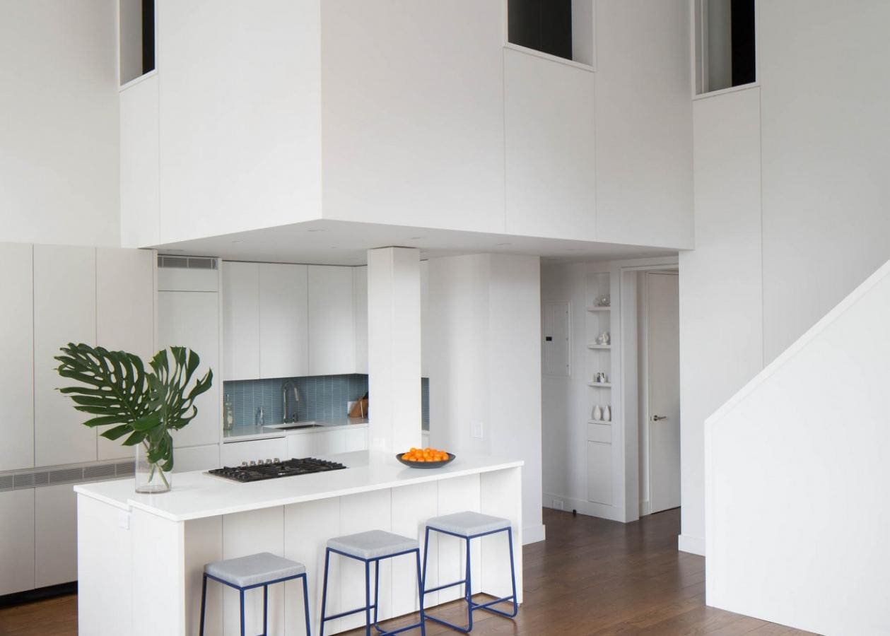 Modern kitchen with white walls, island, and bar stools.