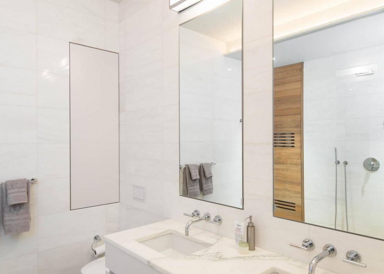 Modern bathroom with white walls, a large mirror, and minimalist decor.