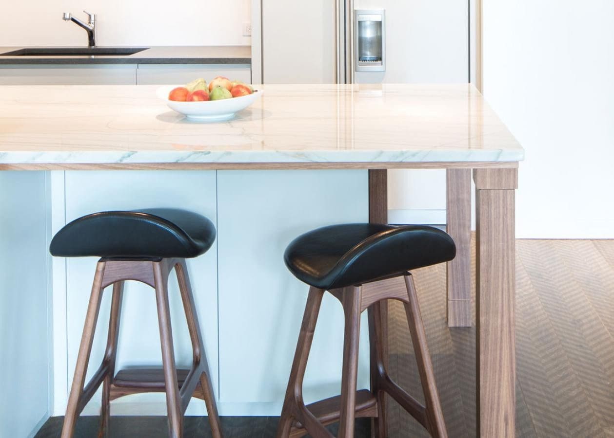Modern kitchen island with two black cushioned bar stools.