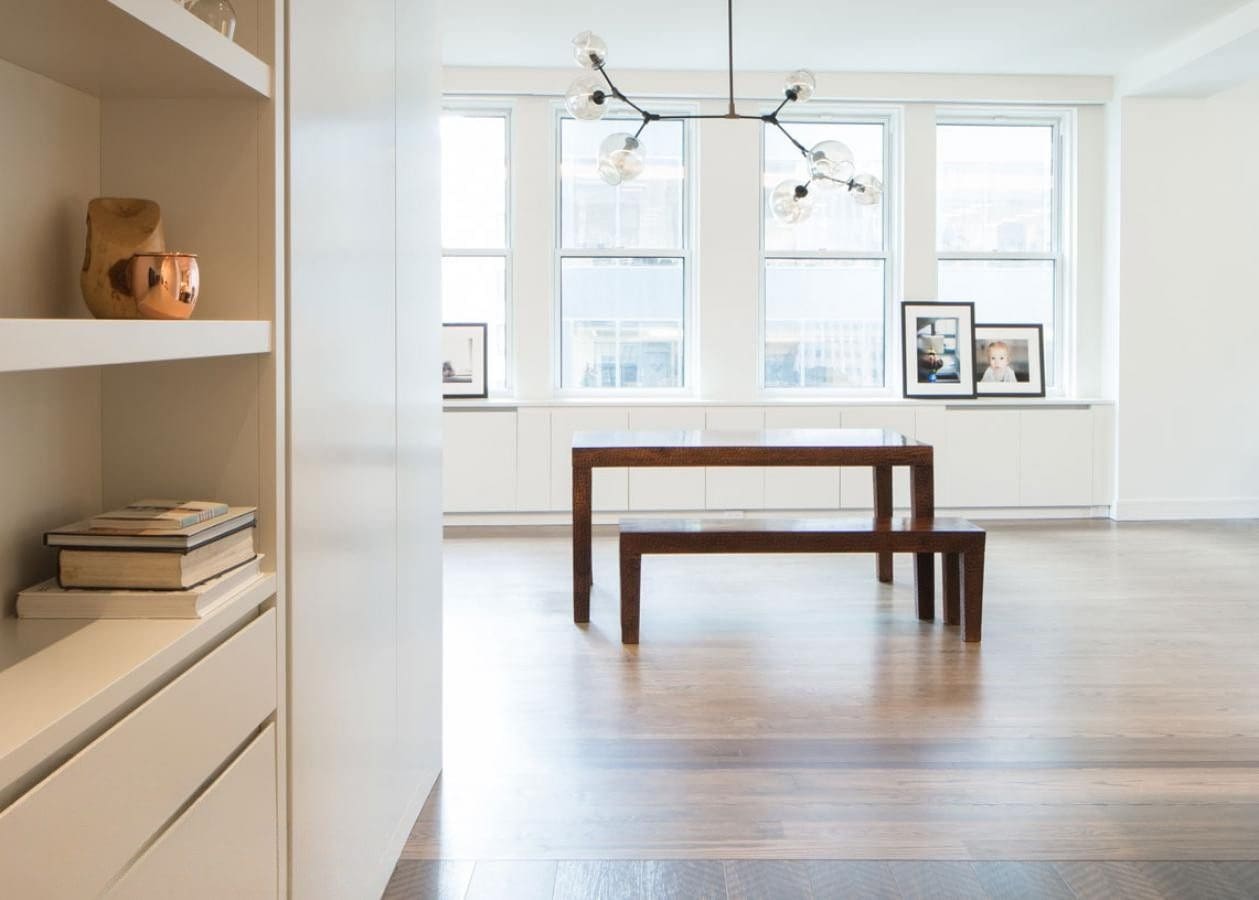 Minimalist dining area with wooden table and large windows.