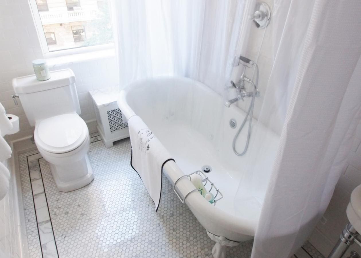 Bright, airy bathroom with a vintage clawfoot tub and white decor.