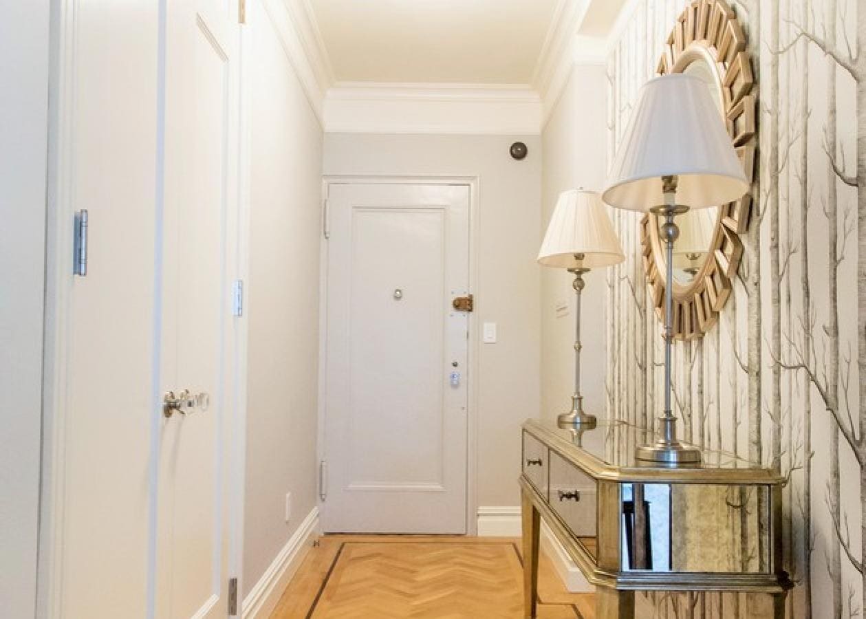 Bright hallway with a white front door and mirrored console table.