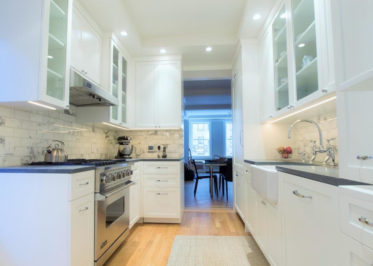Bright modern kitchen with white cabinets and black countertops.