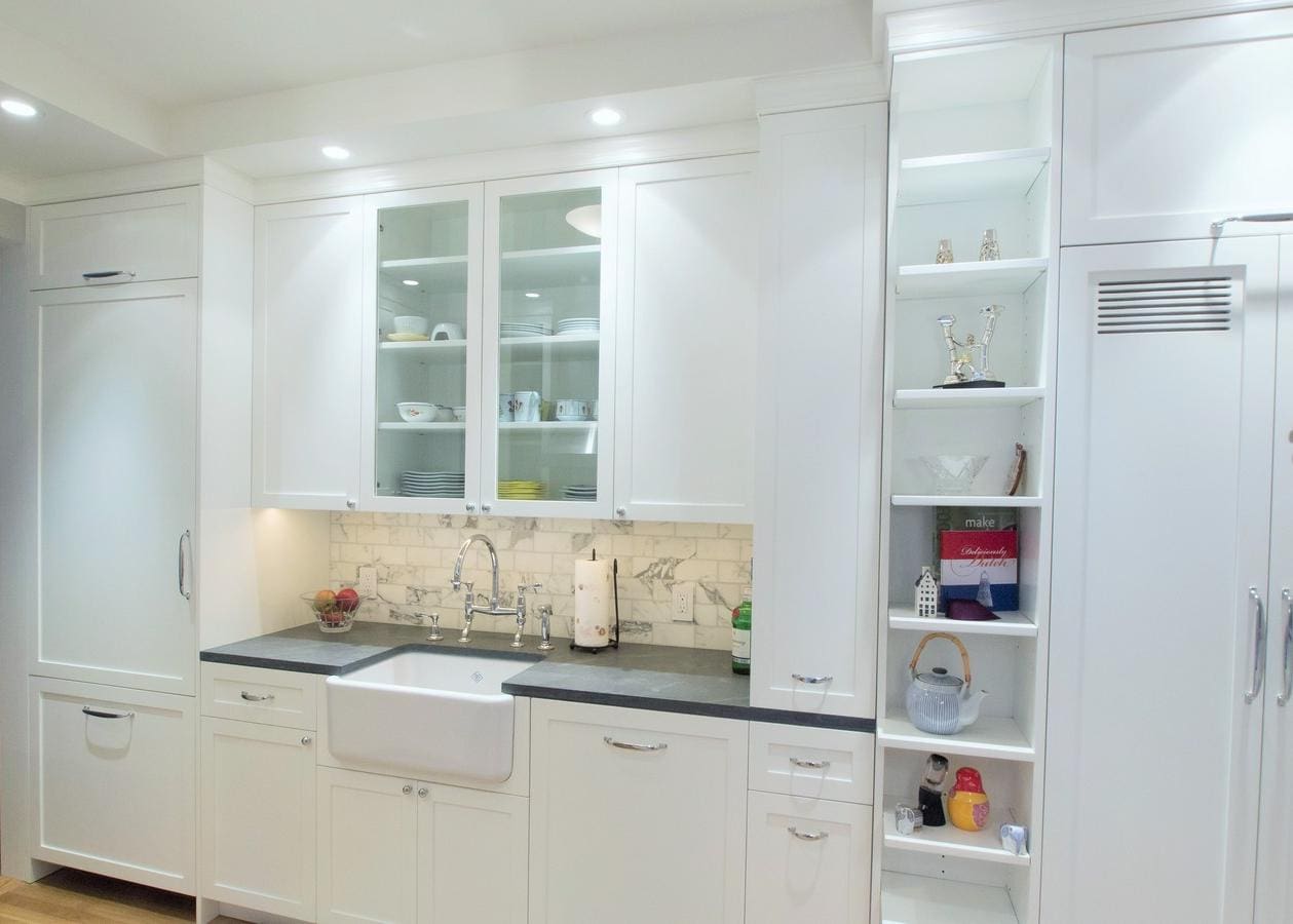 Modern white kitchen with glass cabinets and open shelving.