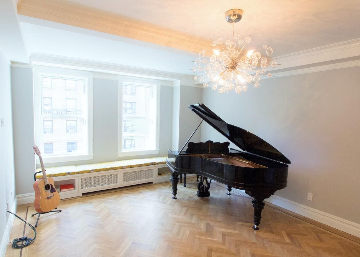 Elegant black grand piano in a bright, minimalist room with large windows.
