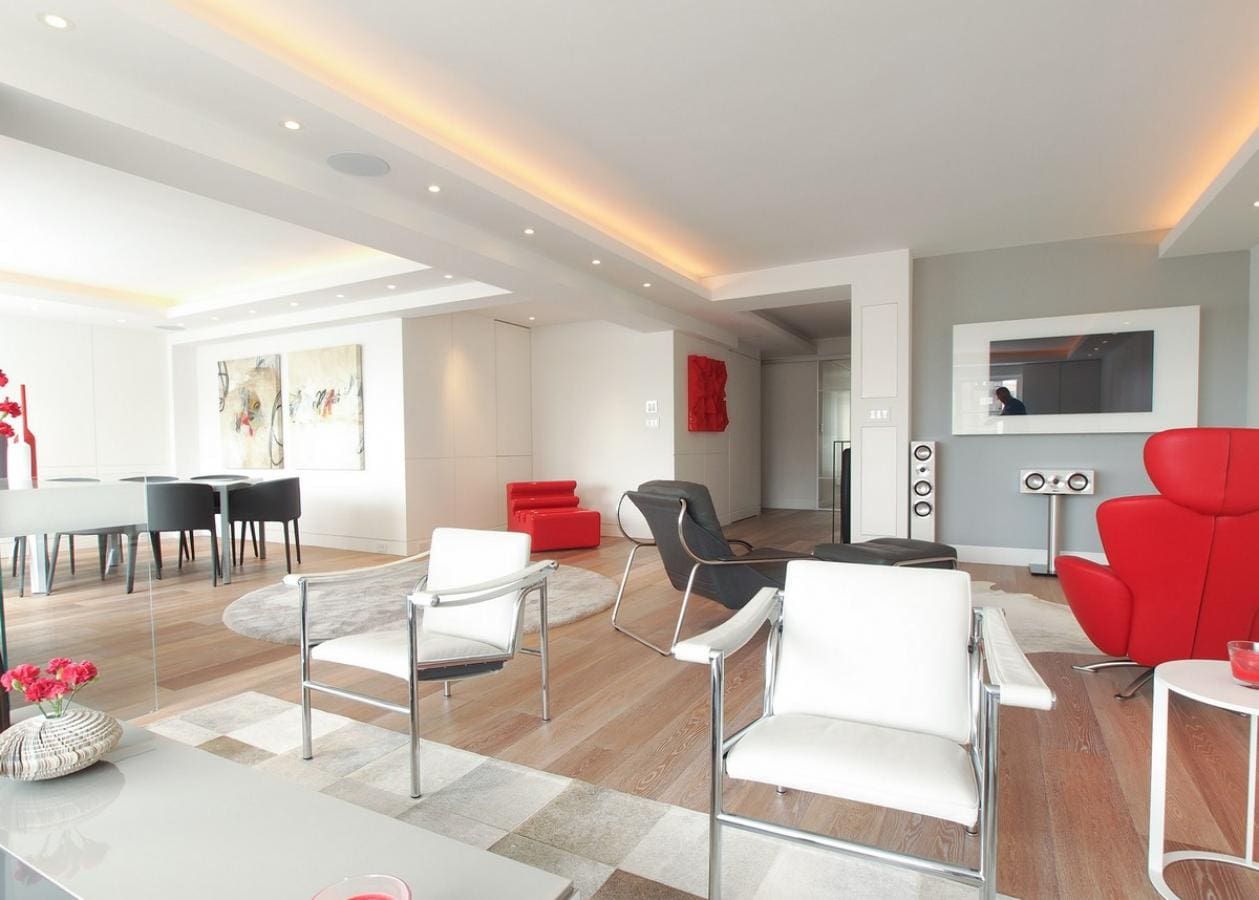 Modern living room with sleek furniture and a grand piano in the background.