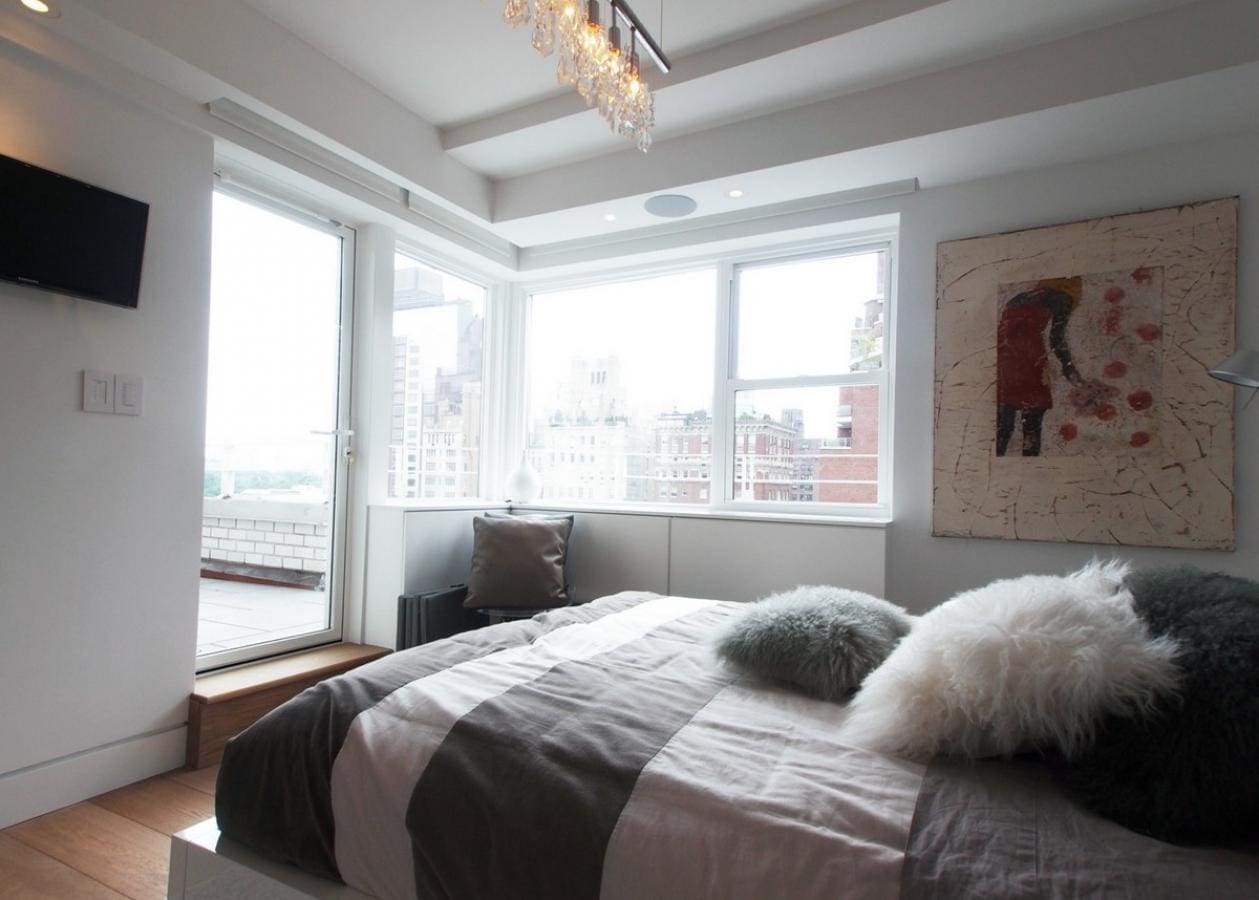 Bright bedroom with large windows and a cozy bed.