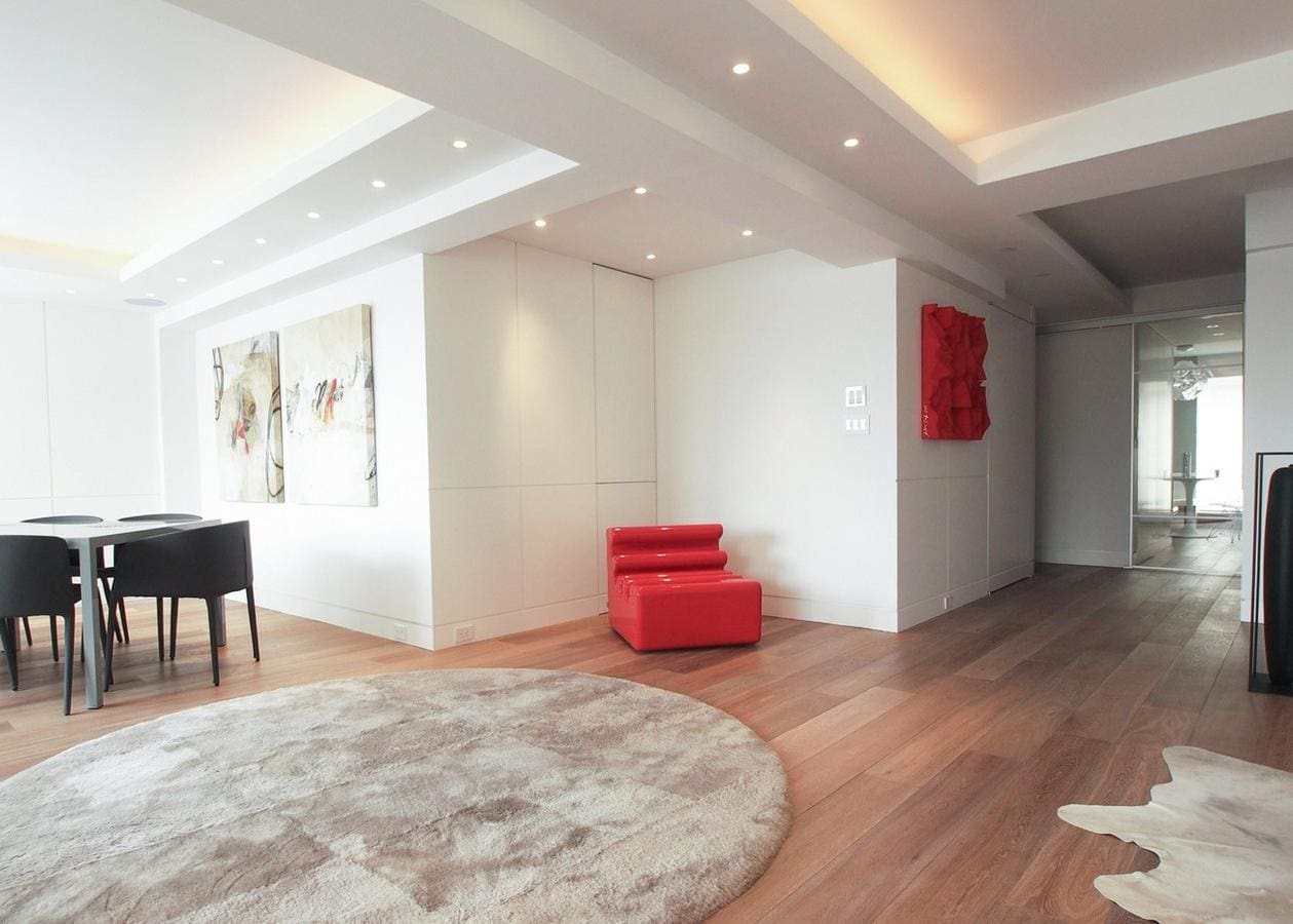 Modern living room with red chairs and wooden flooring.