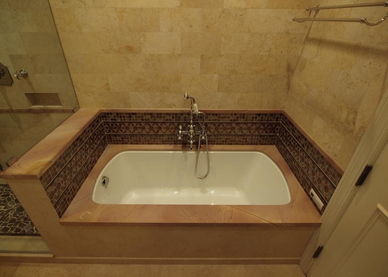 A built-in bathtub with tiled surroundings and wall-mounted faucet.