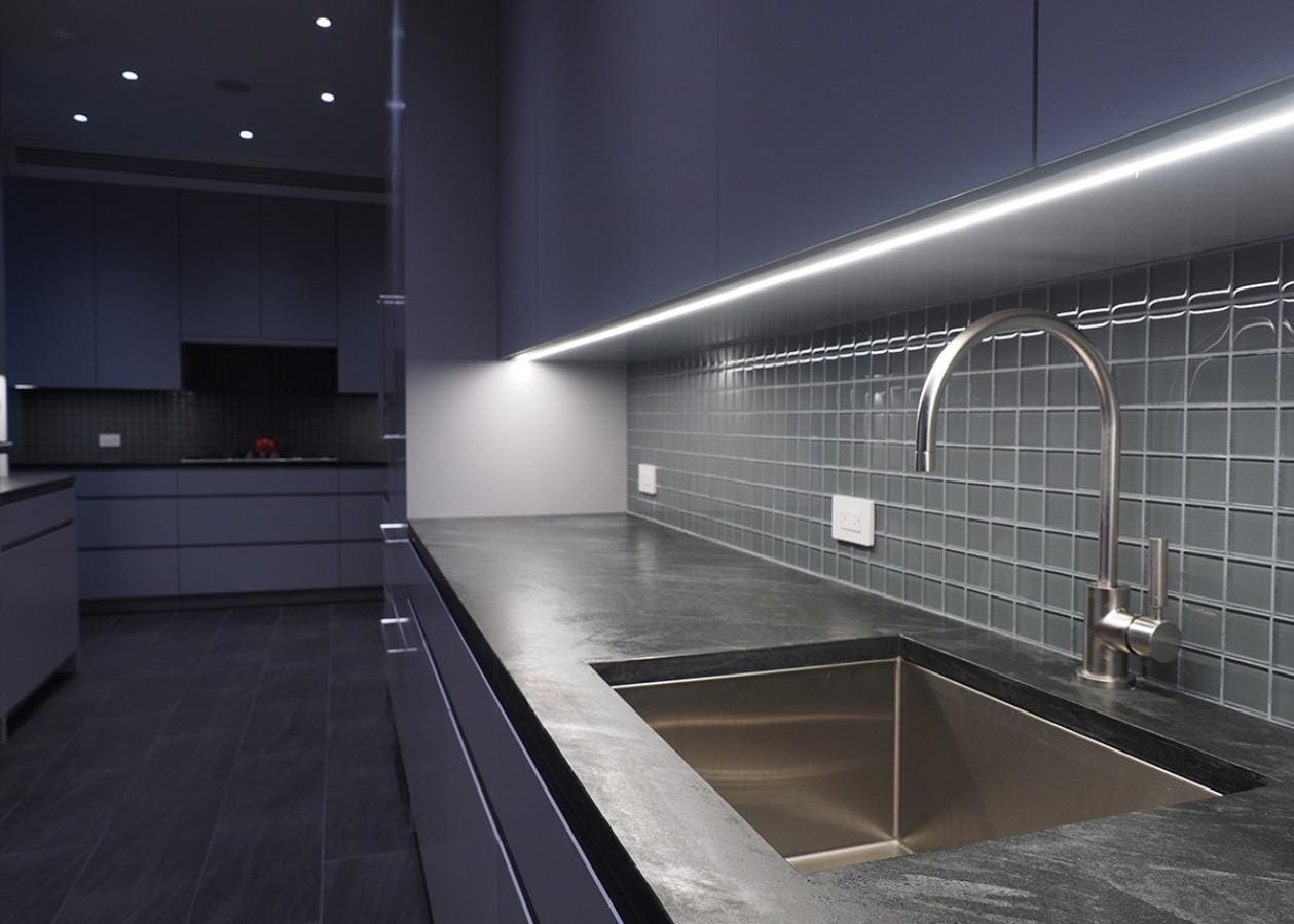 Modern kitchen with sleek black countertops and under-cabinet lighting.