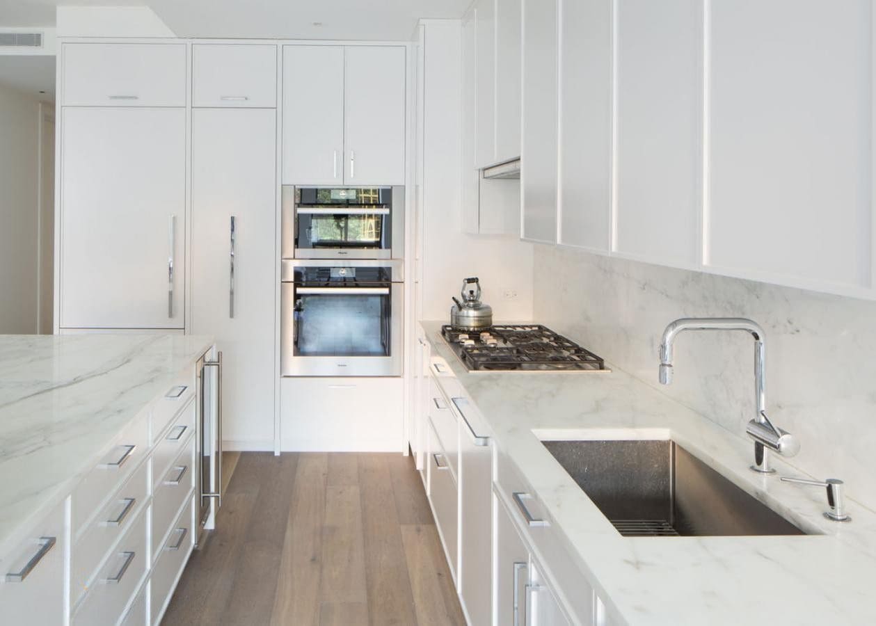 Bright modern kitchen with white cabinets and stainless steel appliances.