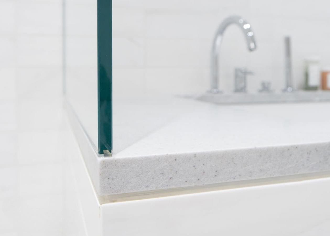 Close-up of a glass shower door on a clean white bathroom surface.