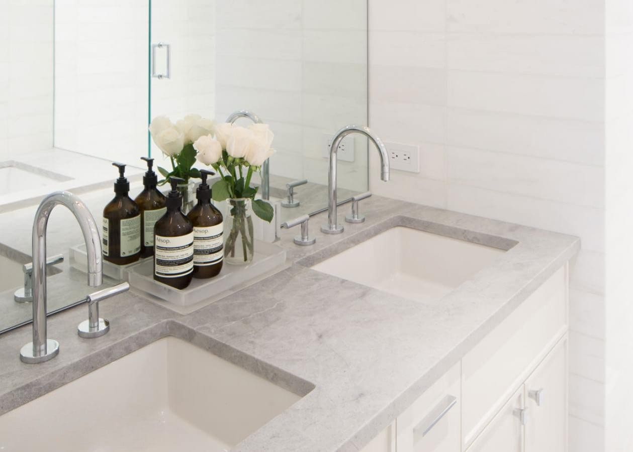 Elegant white bathroom countertop with dual sinks and decorative vases.