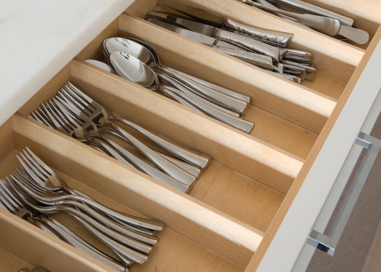 Organized silverware in a kitchen drawer with wooden dividers.
