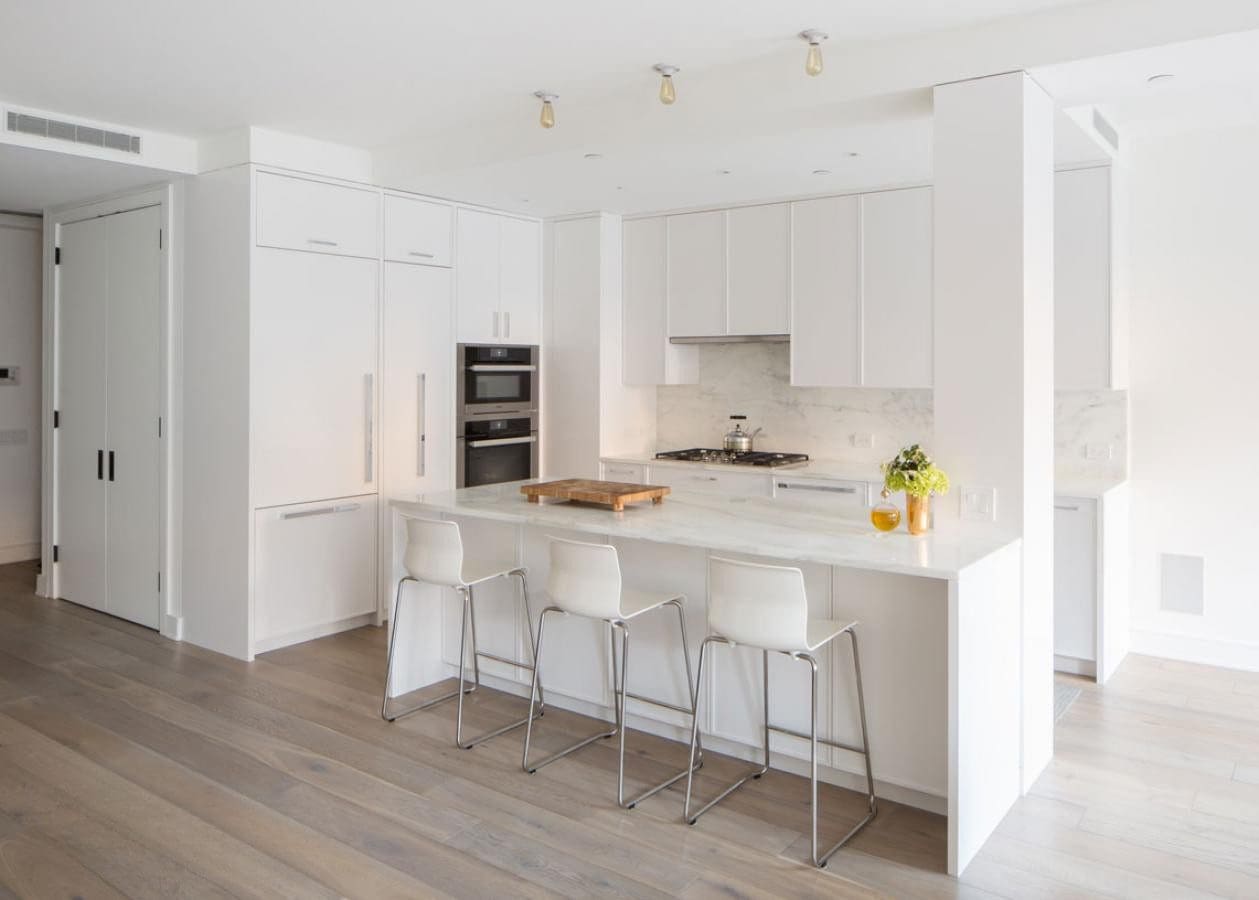 Modern white kitchen with island and bar stools.