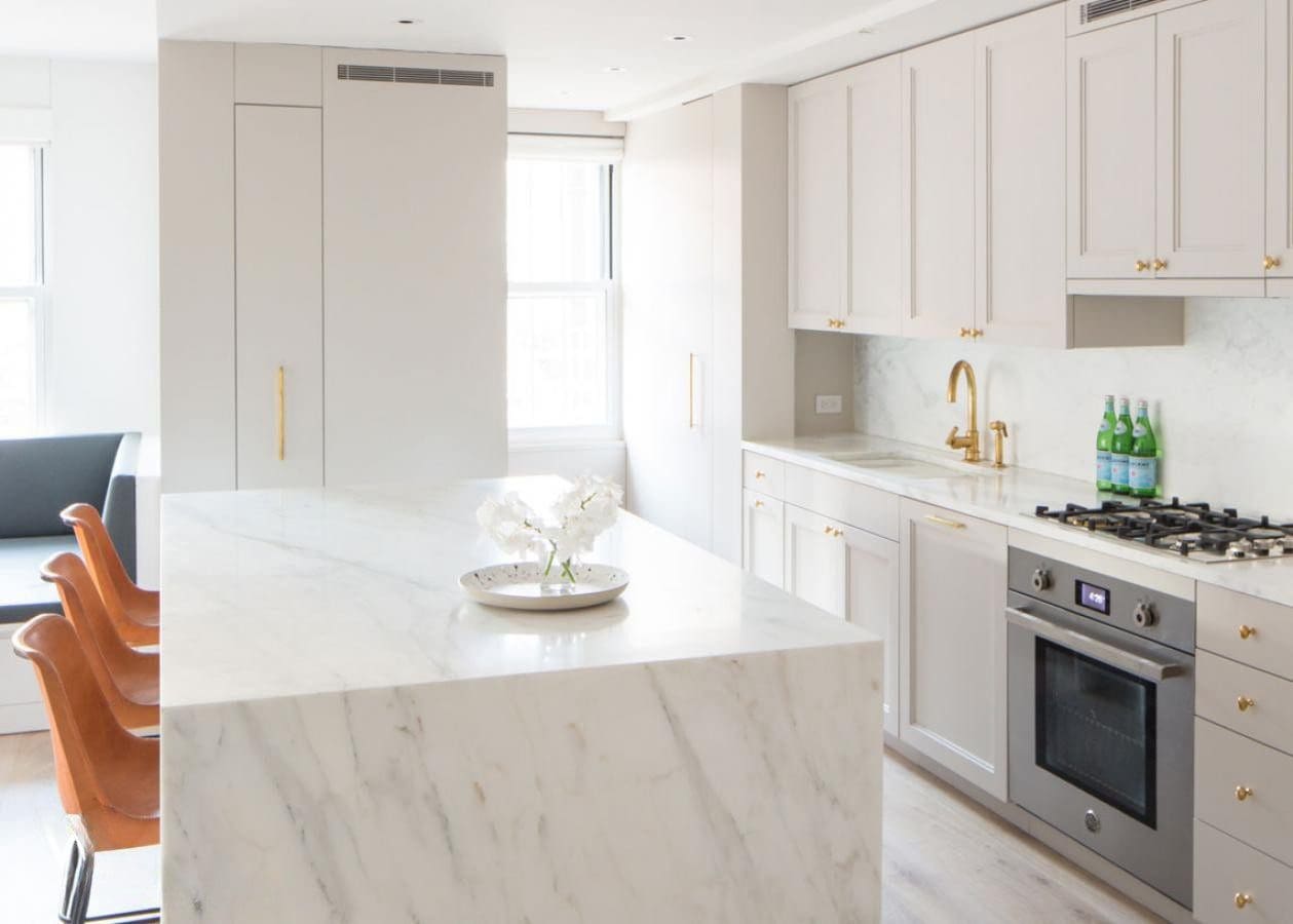 Bright modern kitchen with marble island and white cabinetry.