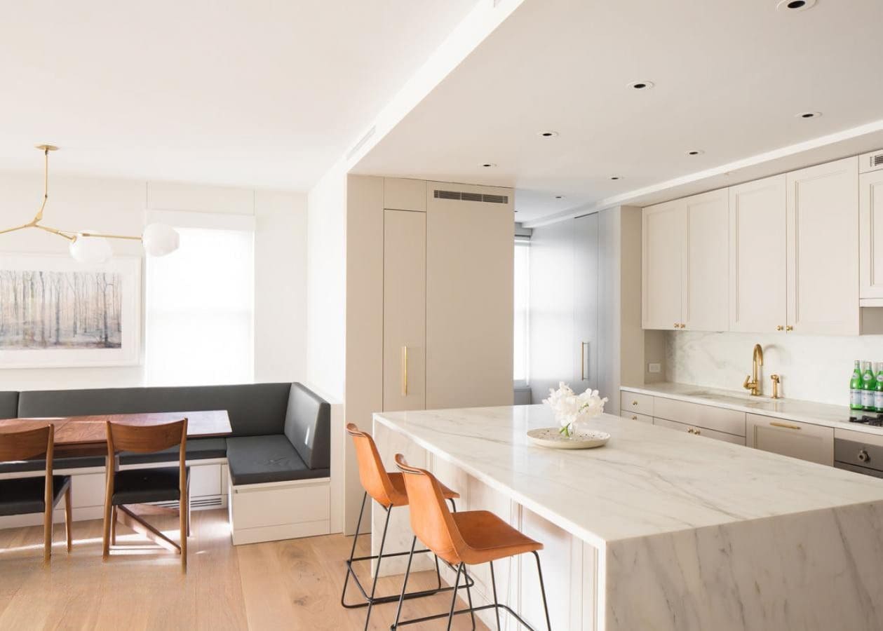 Modern kitchen and dining area with marble island and bar stools.
