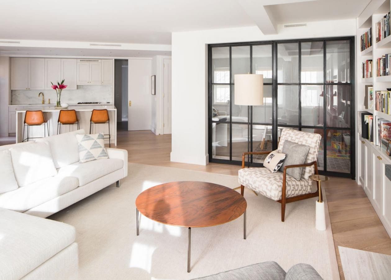 Bright modern living room with white furniture and a wooden coffee table.