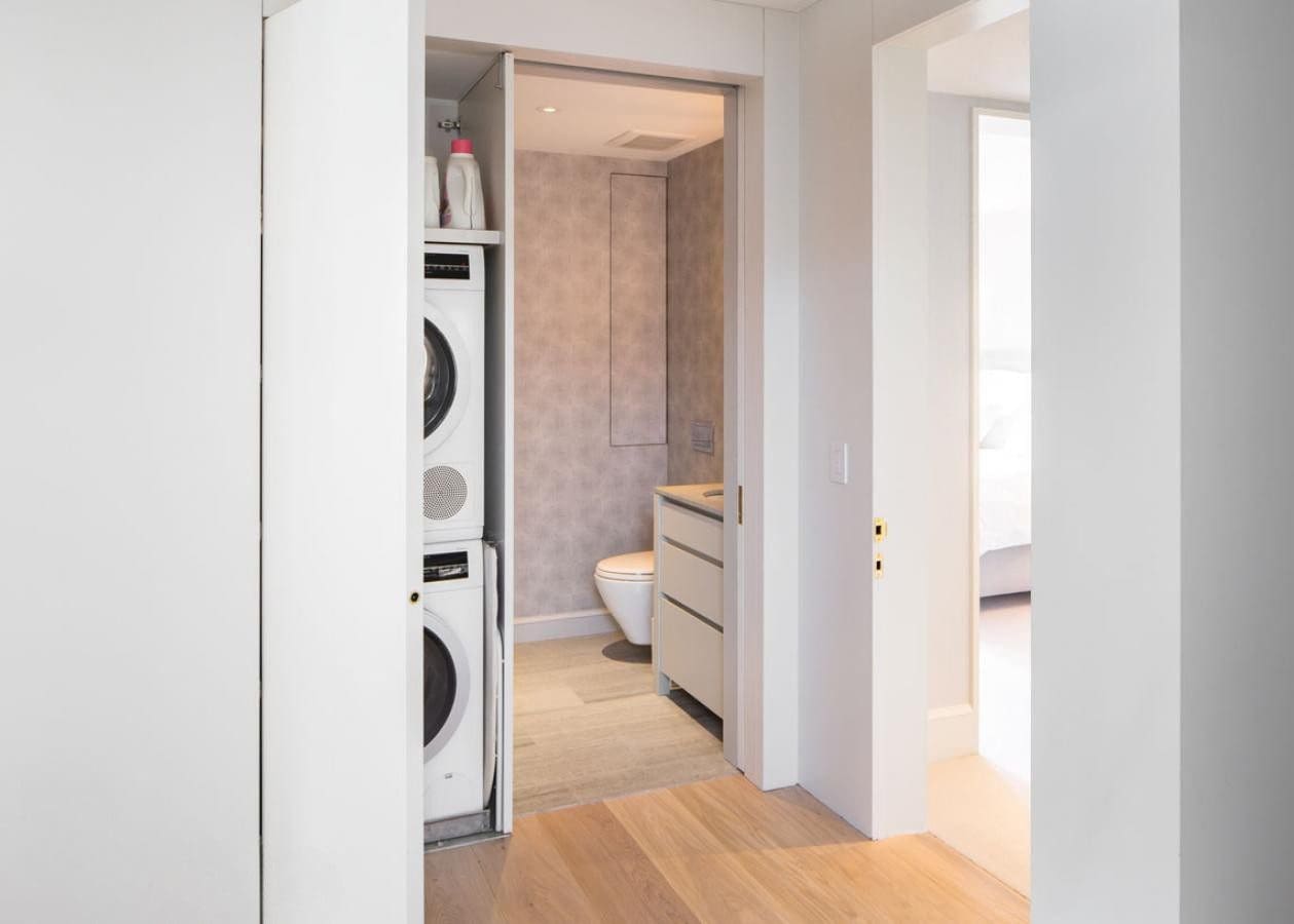 Compact laundry area with stacked washer and dryer in a modern hallway.