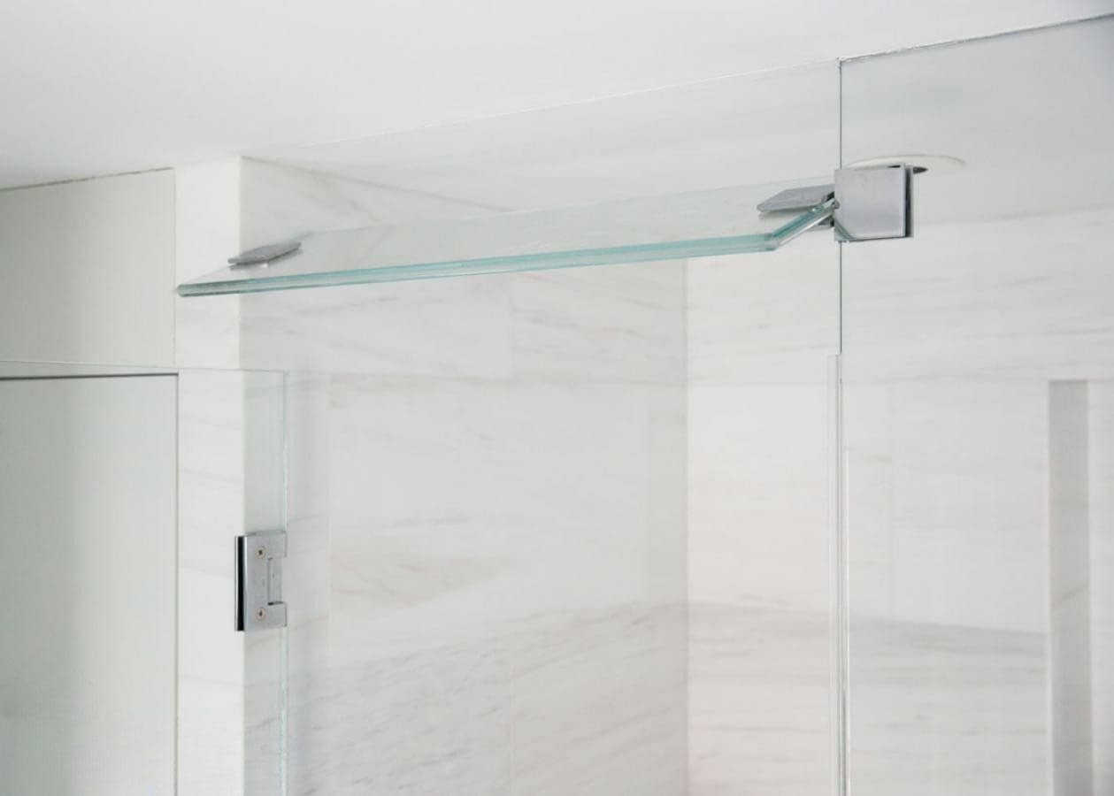 Modern glass shower door with metal support bar in a bright bathroom.