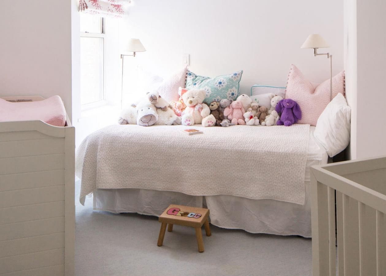 Cozy bedroom with stuffed animals and a small wooden step stool.