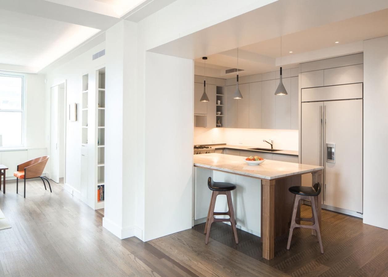 Modern kitchen with white cabinets and wooden stools at the island.