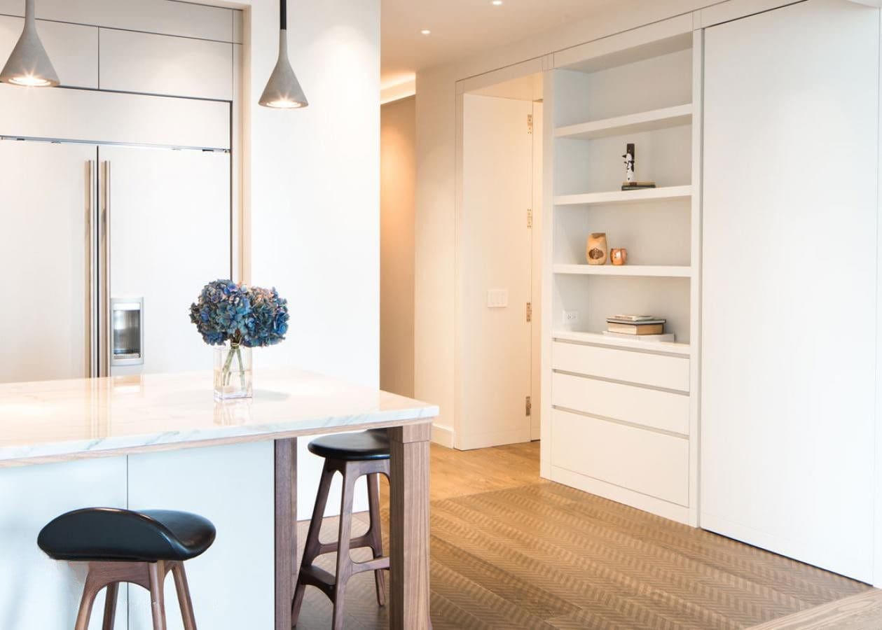 Bright modern kitchen with white cabinetry and wooden stools.