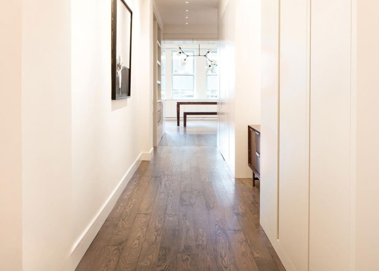 Bright hallway with wooden flooring leading to a dining area.